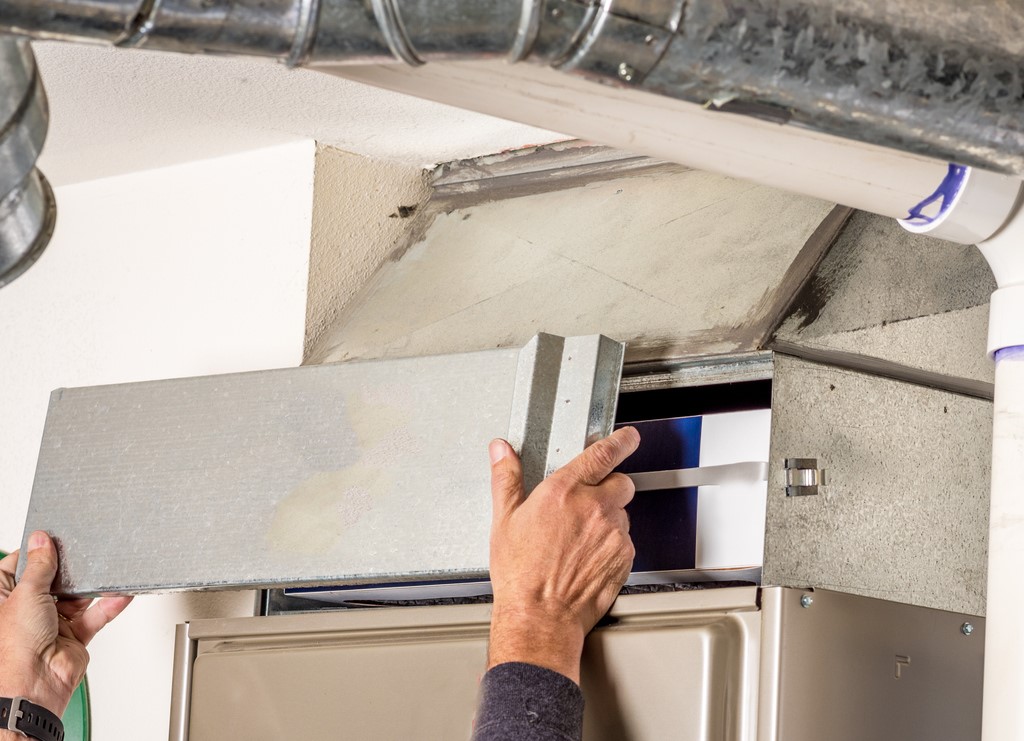 HVAC technician removing access panel on furnace