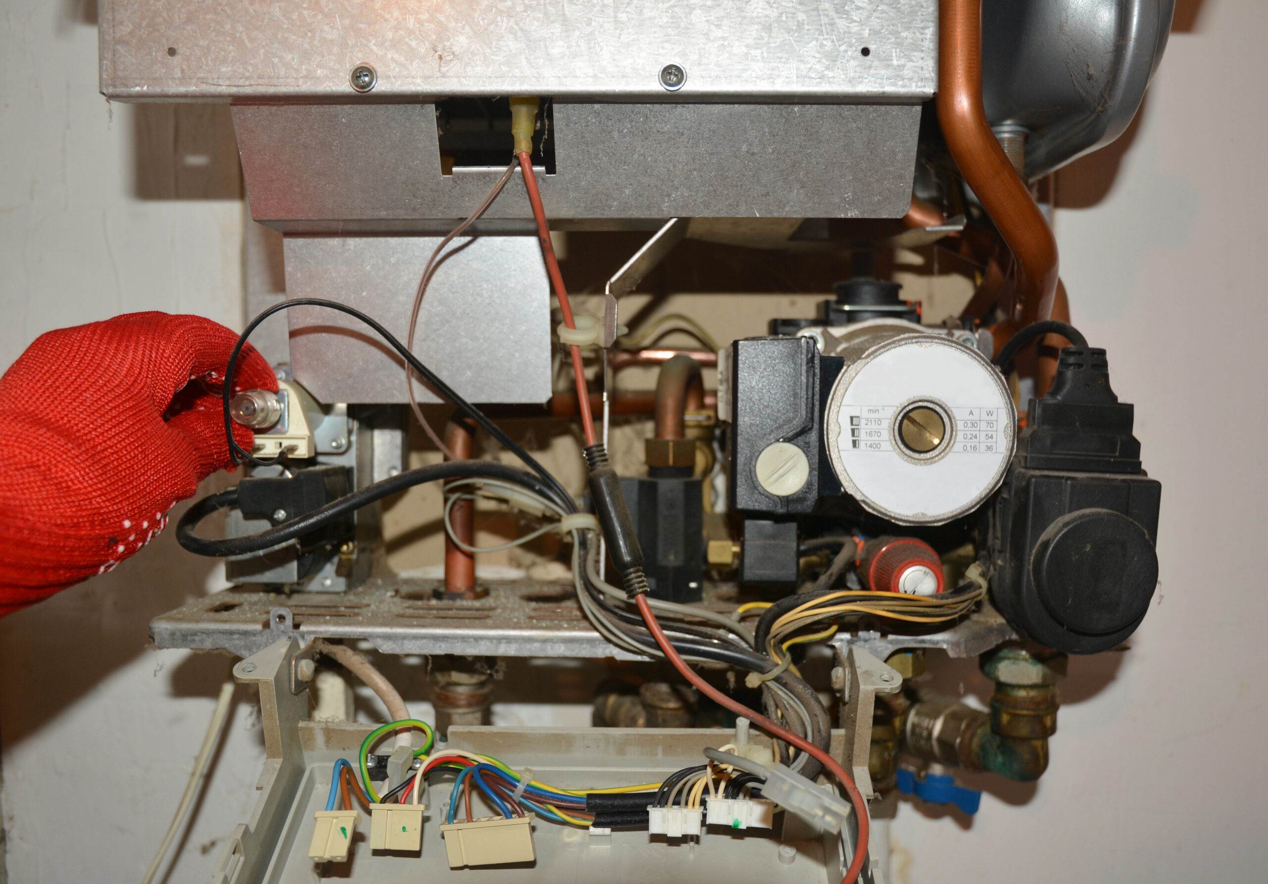 Red-gloved technician repairing a gas boiler